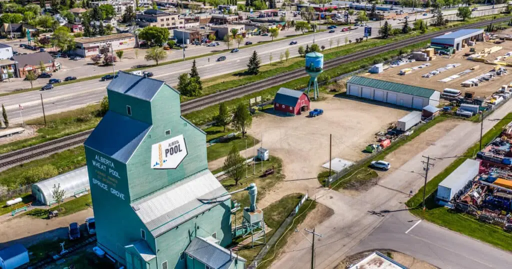 Aerial view of Spruce Grove, AB featuring a community pool, sports facilities, and surrounding commercial areas.