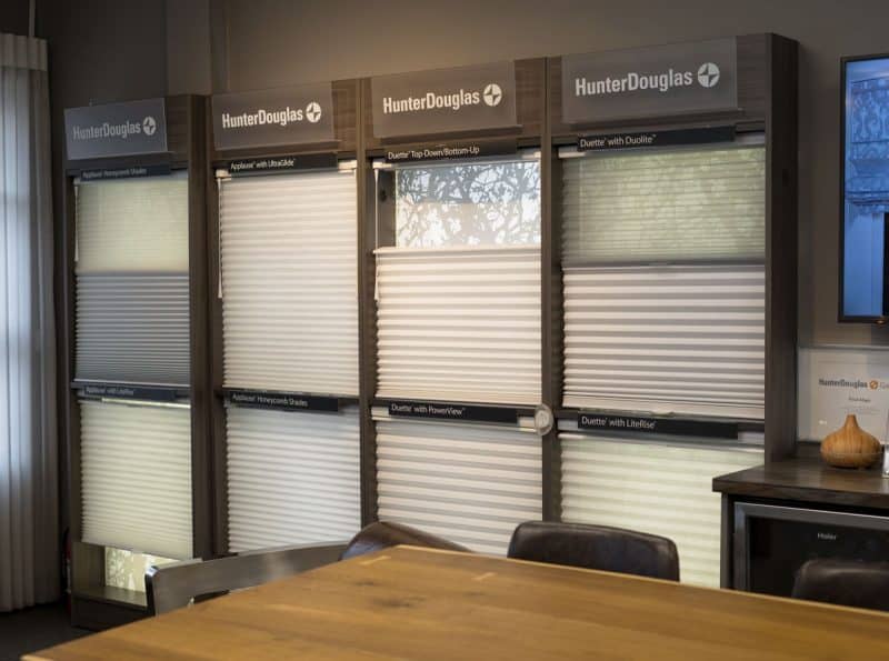 Hunter Douglas window blinds display with various styles and textures in interior setting.