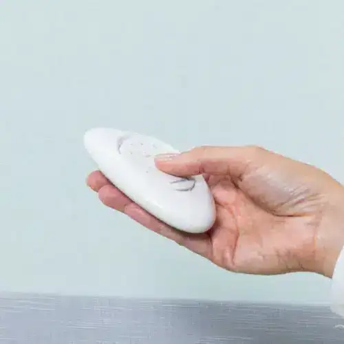 A hand holding a white soap bar against a light background.