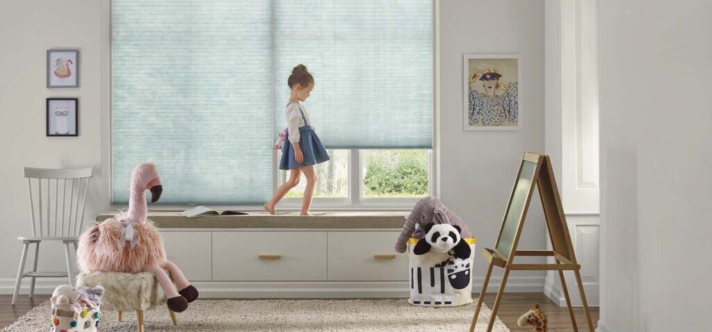 Bright playroom with girl, stuffed animals, toys, and artwork, featuring a large window and playful decor.