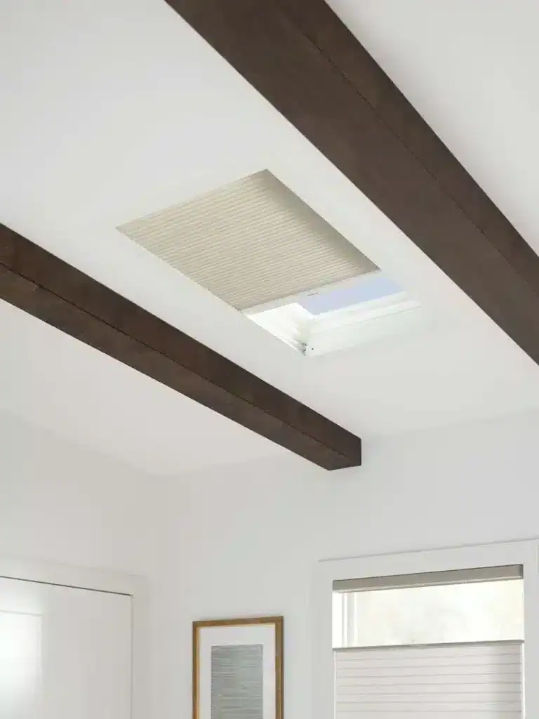 Ceiling vent with a skylight and wooden beams in a bright modern home interior.