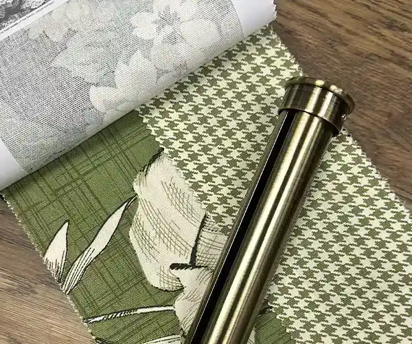 A close-up of fabric swatches featuring floral, checkered, and houndstooth patterns on a wooden surface with a metal roller.