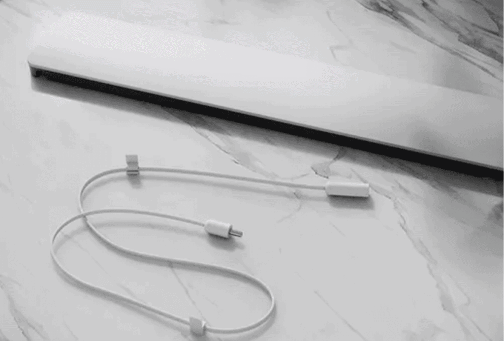 White laptop power cable with inline connector on a marble surface.
