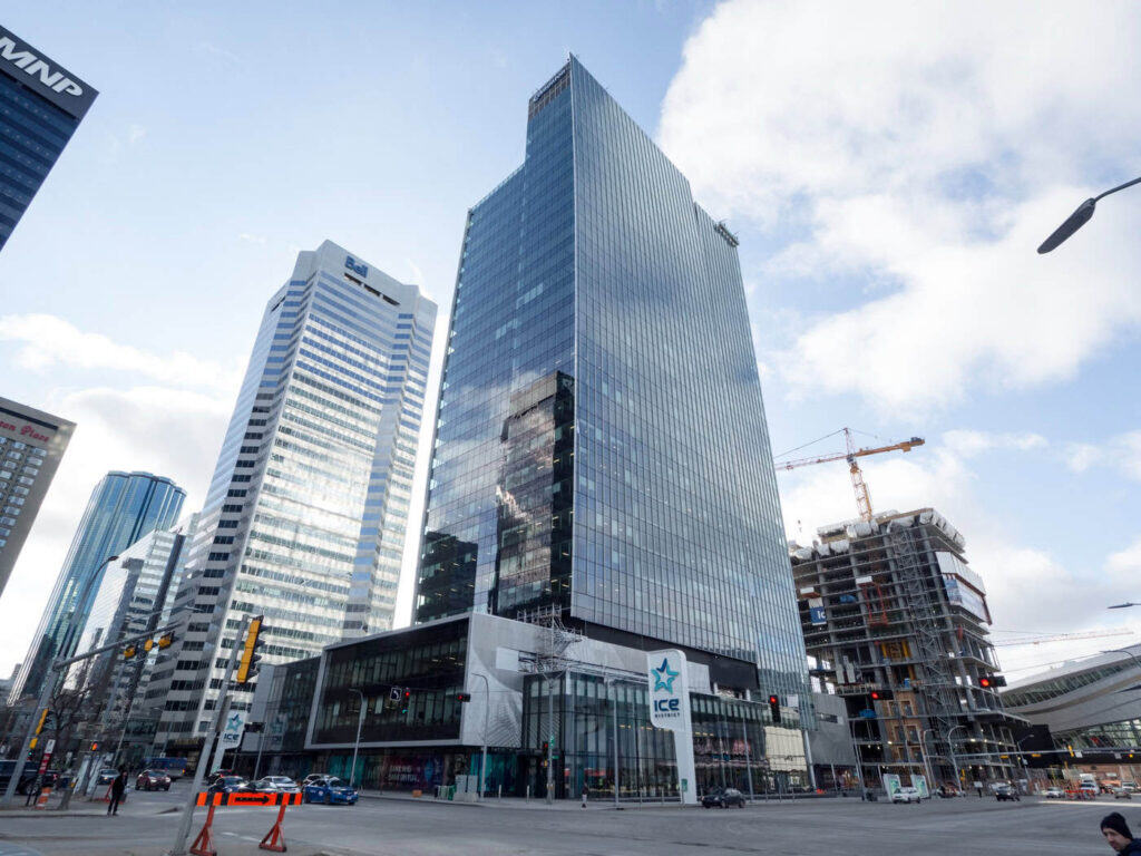 EDMONTON TOWER SKYLINE - Modern glass skyscraper in downtown Edmonton, Alberta, with surrounding high-rise buildings and ongoing construction, under a partly cloudy sky.