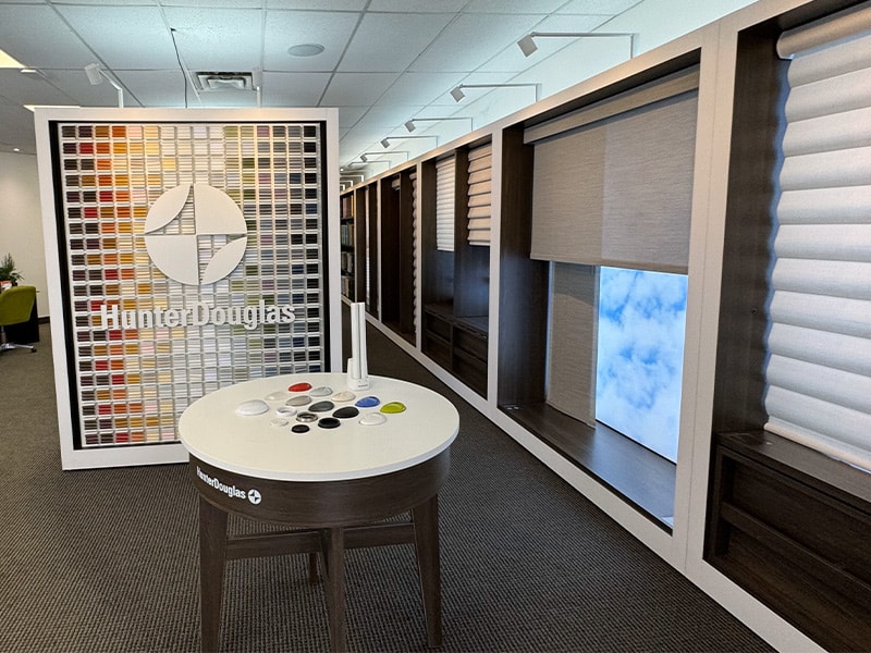 Elegant window coverings with various shades and blinds in a modern showroom setting.