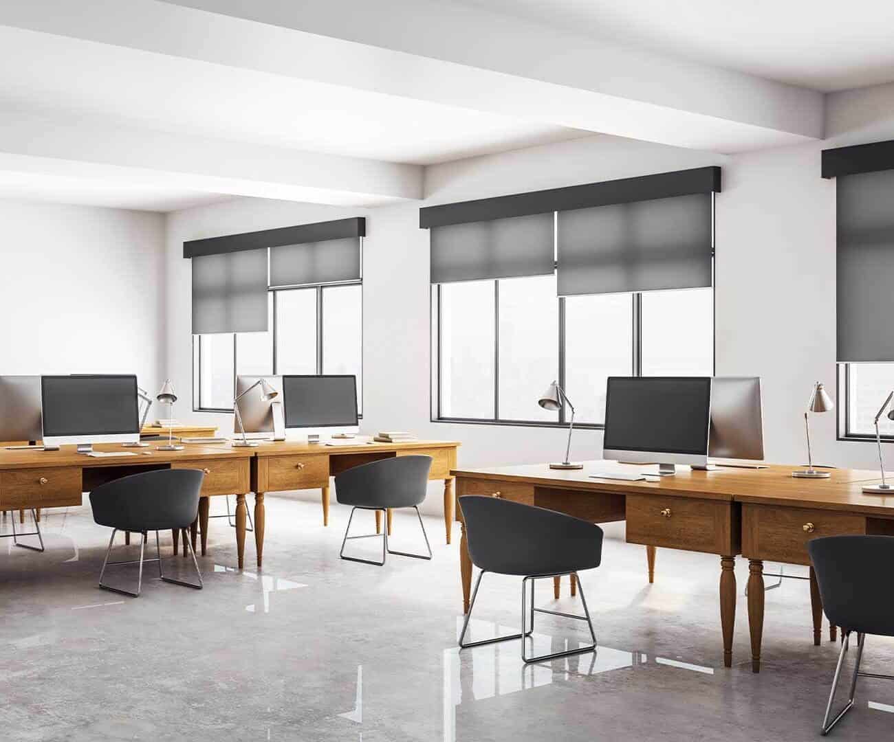 Bright office with large windows fitted with sleek, black commercial blinds providing privacy and light control in a professional workspace.