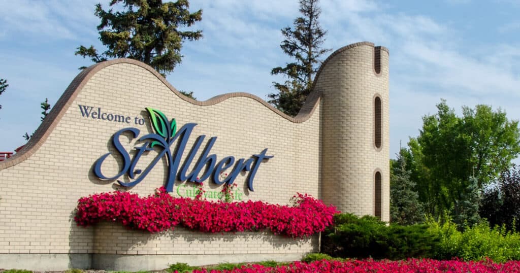 Welcome sign at the entrance of St. Albert, Alberta, featuring vibrant flowers and lush greenery.