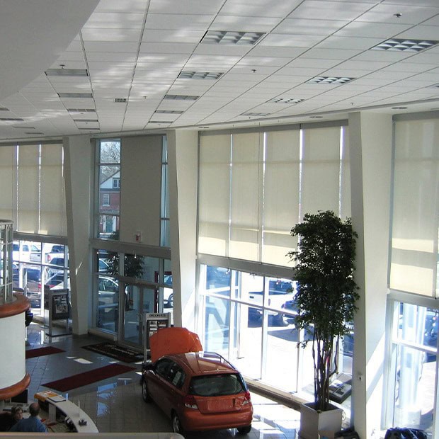 Bright interior of Sherwood Buick GMC dealership featuring large windows, a sleek red car, and contemporary design elements for a welcoming automotive shopping experience.