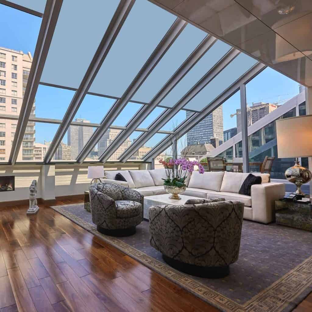 Elegant commercial blinds covering expansive glass windows in a modern office space. Bright natural light filters through, highlighting stylish furnishings and city views.