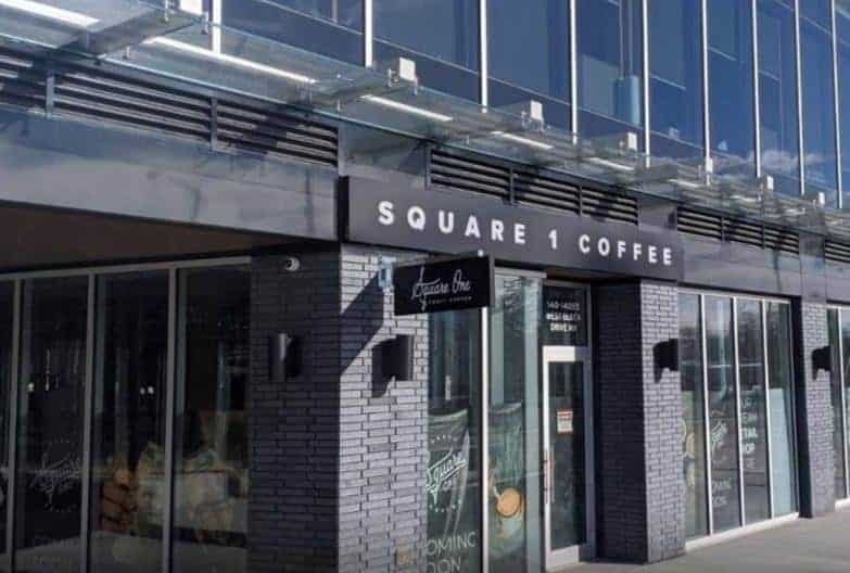 Modern coffee shop entrance with signage "Square 1 Coffee" in an urban setting.